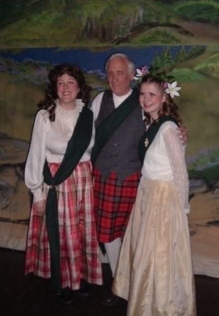 A man in a kilt poses with two women