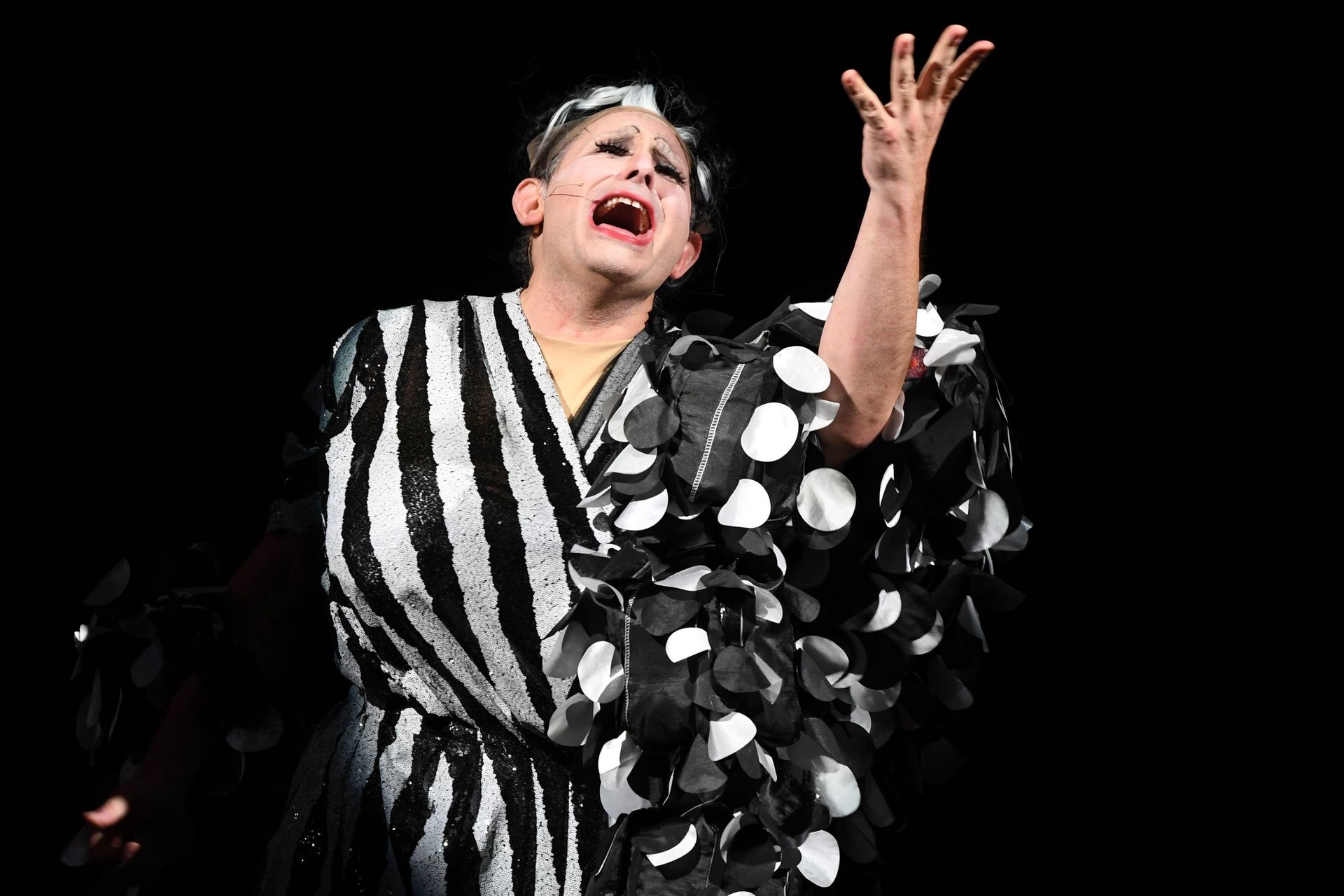 A woman in a black and white polka dot dress is screaming.