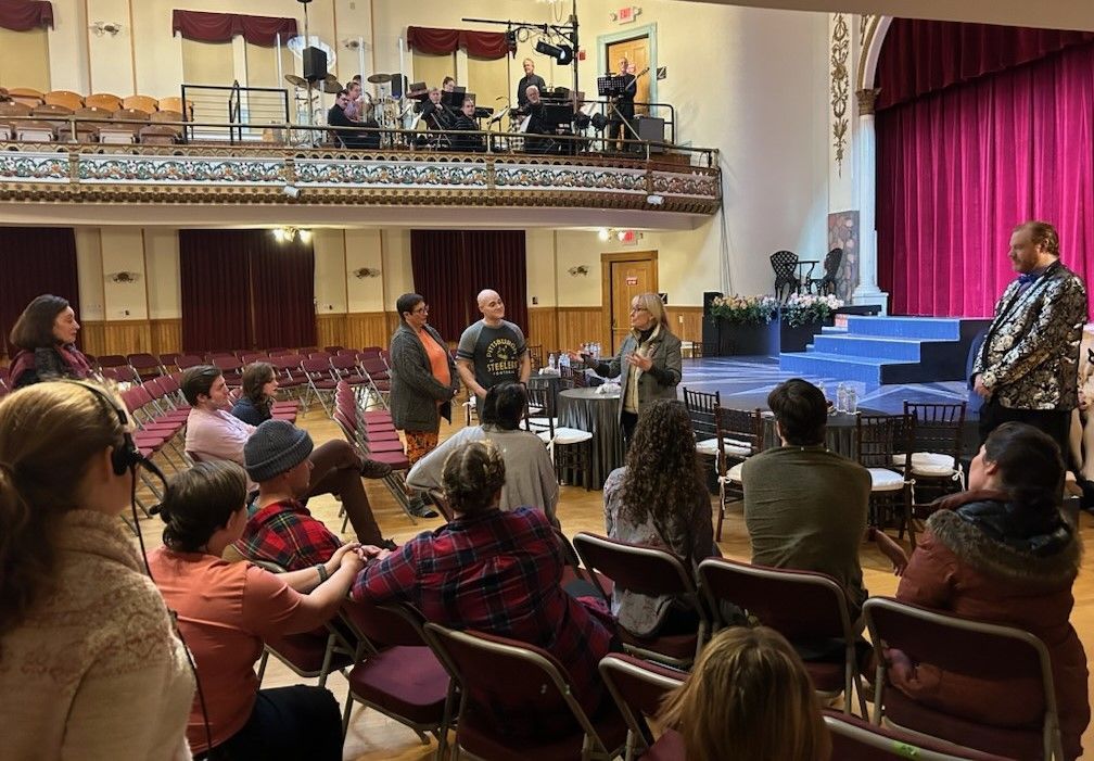 A group of people are sitting in chairs in a large auditorium.