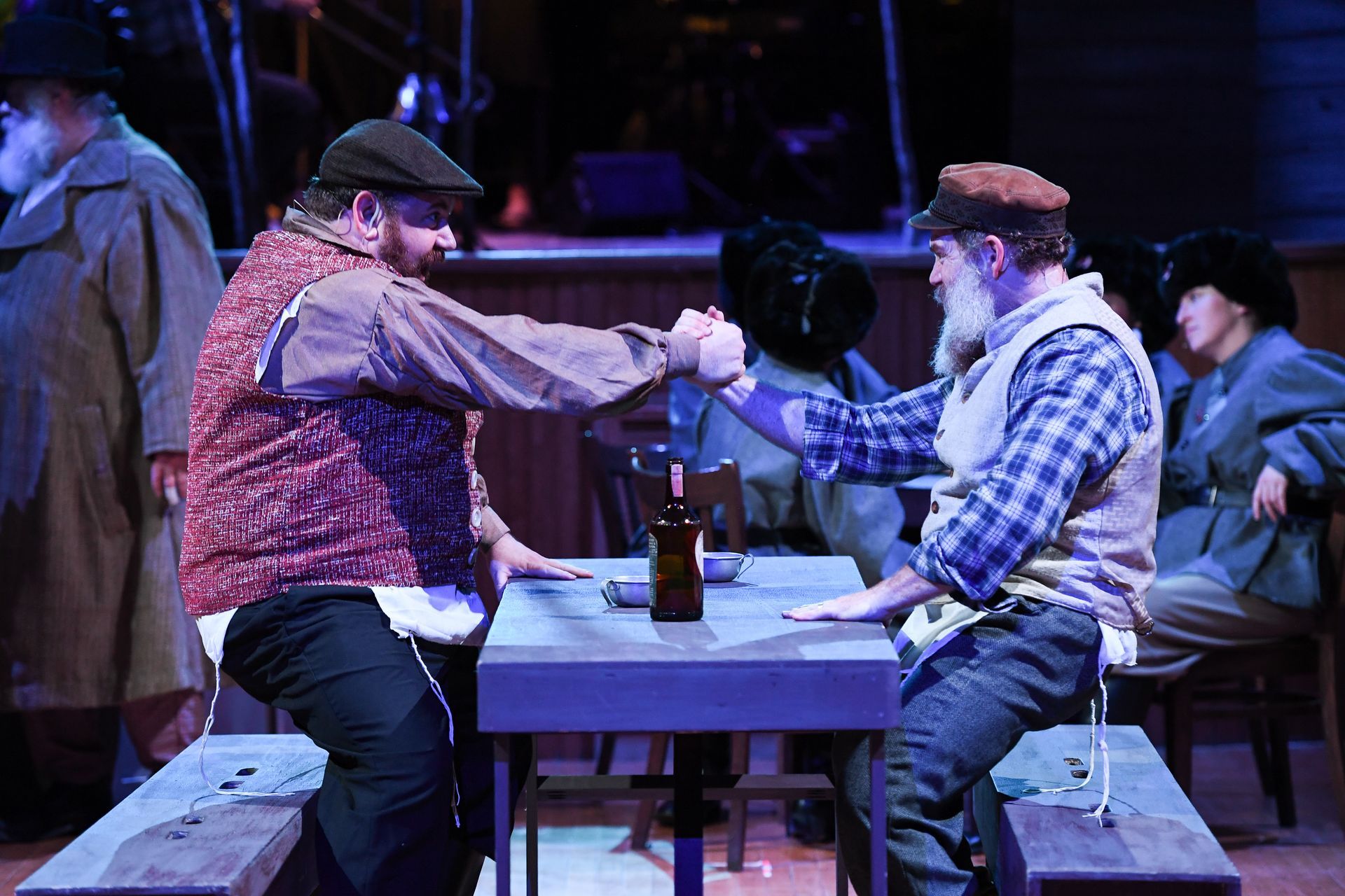Two men are sitting at a table shaking hands.