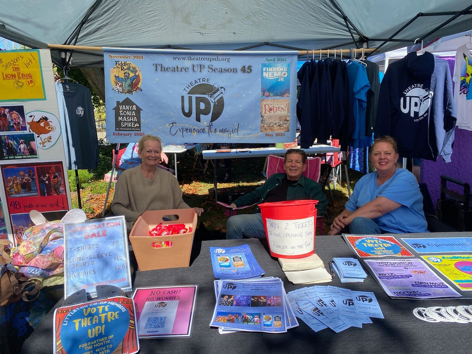 Three people are sitting at a table in front of a sign that says up