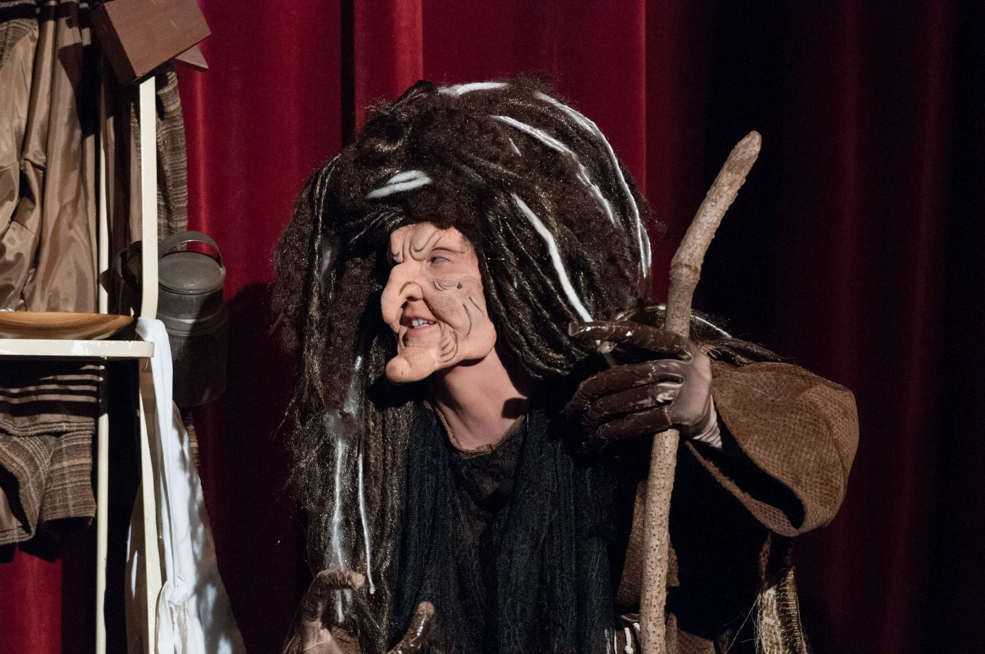 A woman in a witch costume is holding a cane