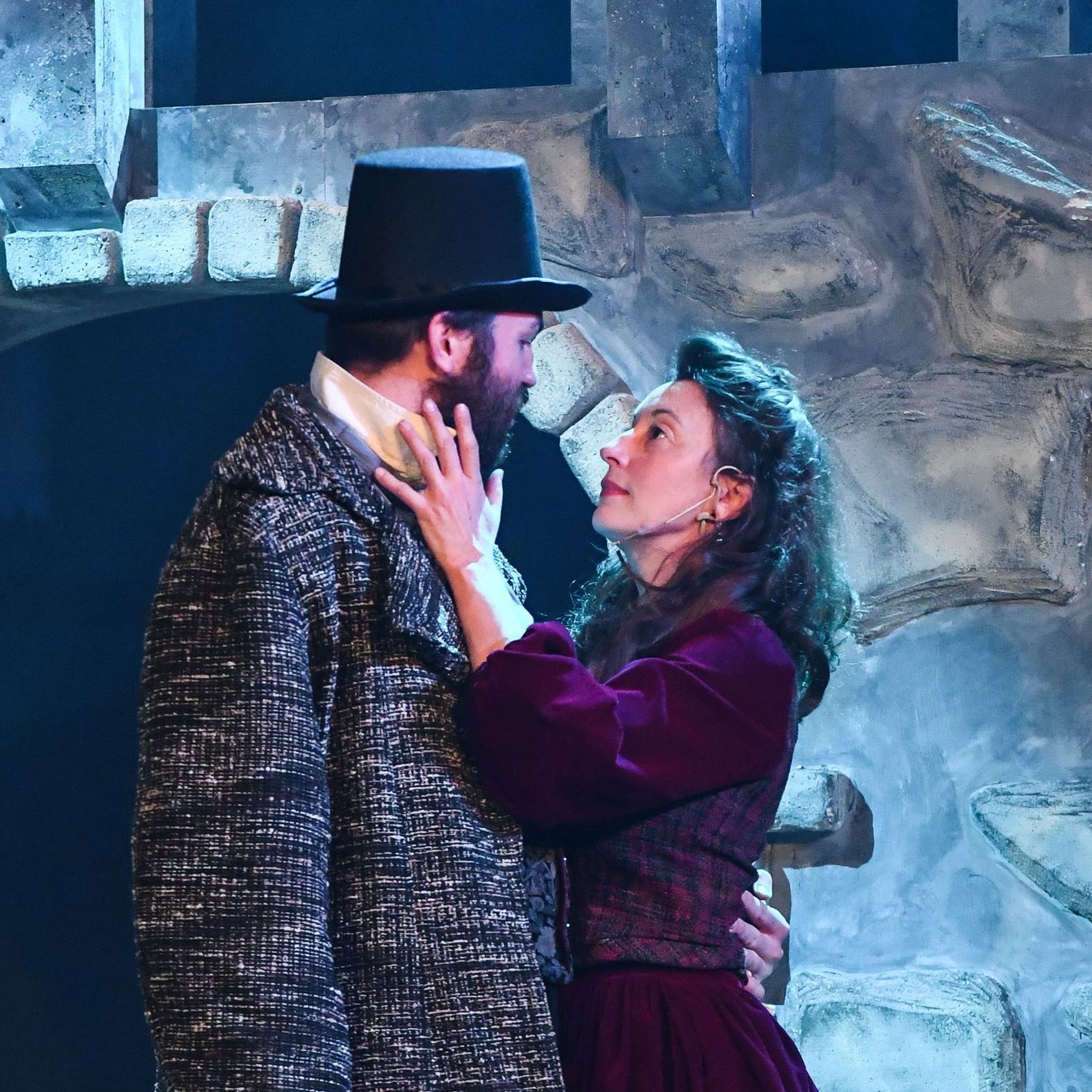 A man in a top hat is kissing a woman in a purple dress