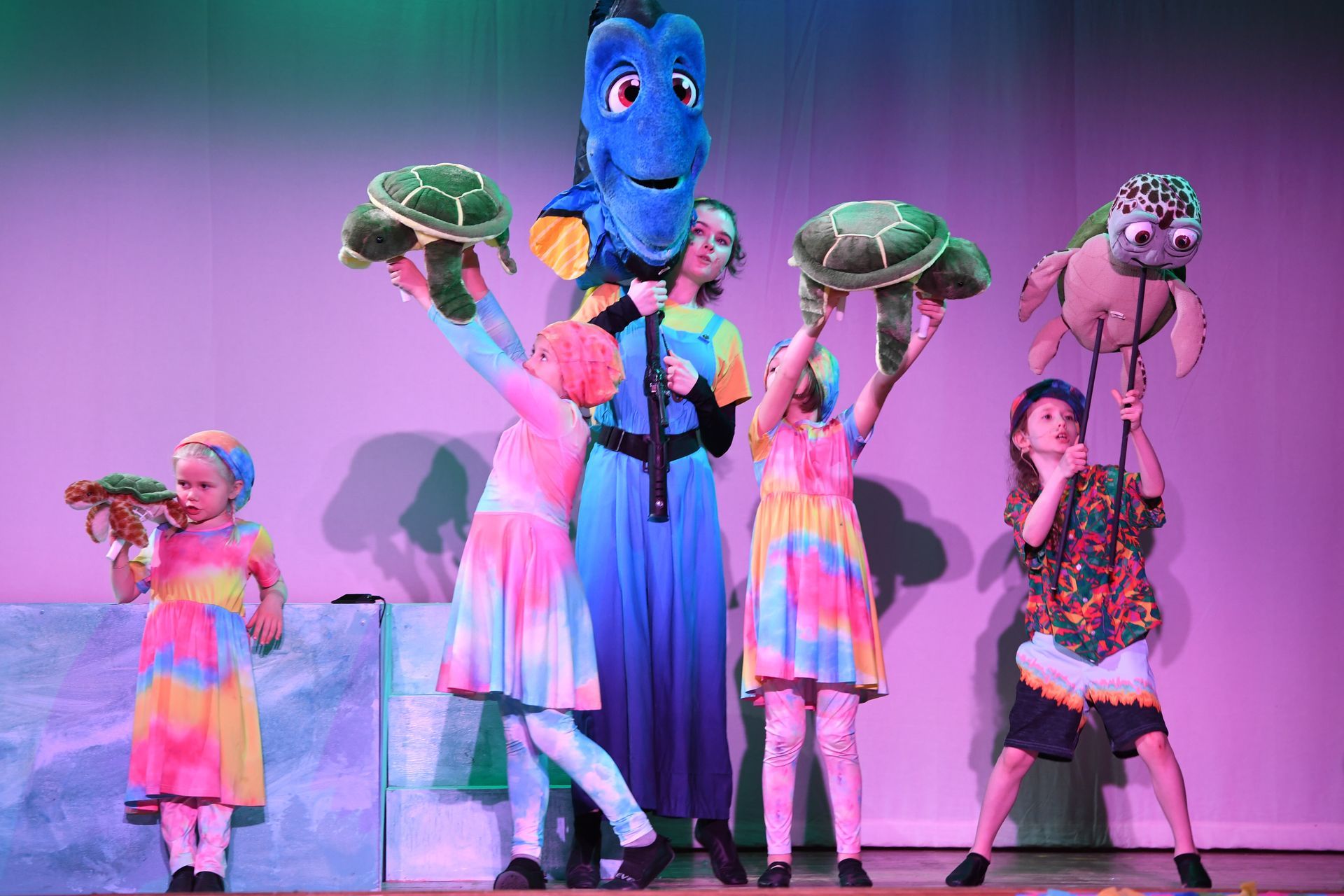A man and a girl are standing next to each other on a stage holding a toucan.