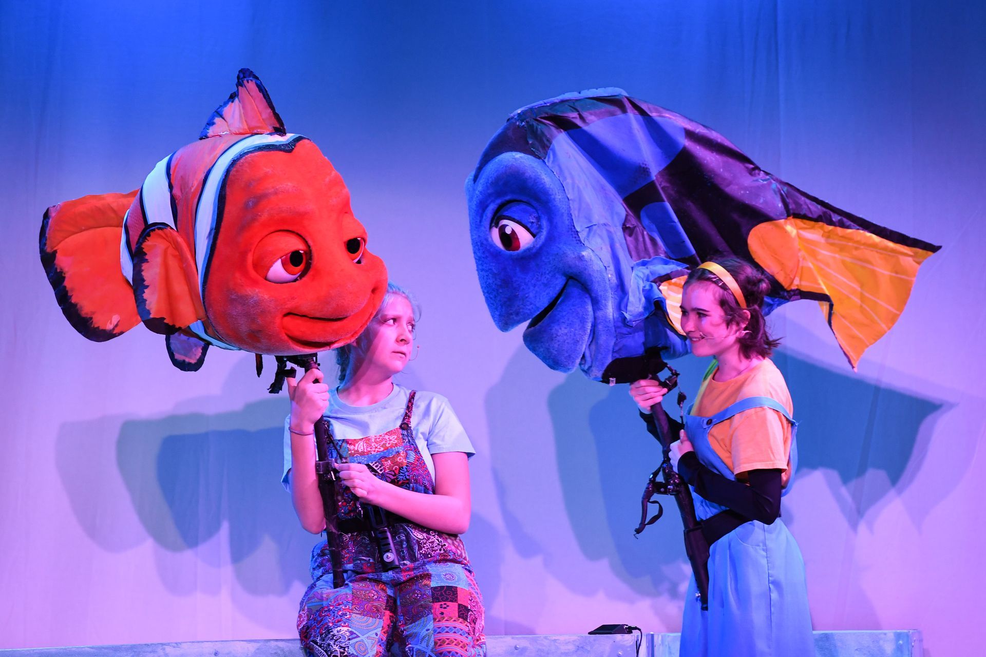 A woman is standing next to a clown fish puppet on a stage.