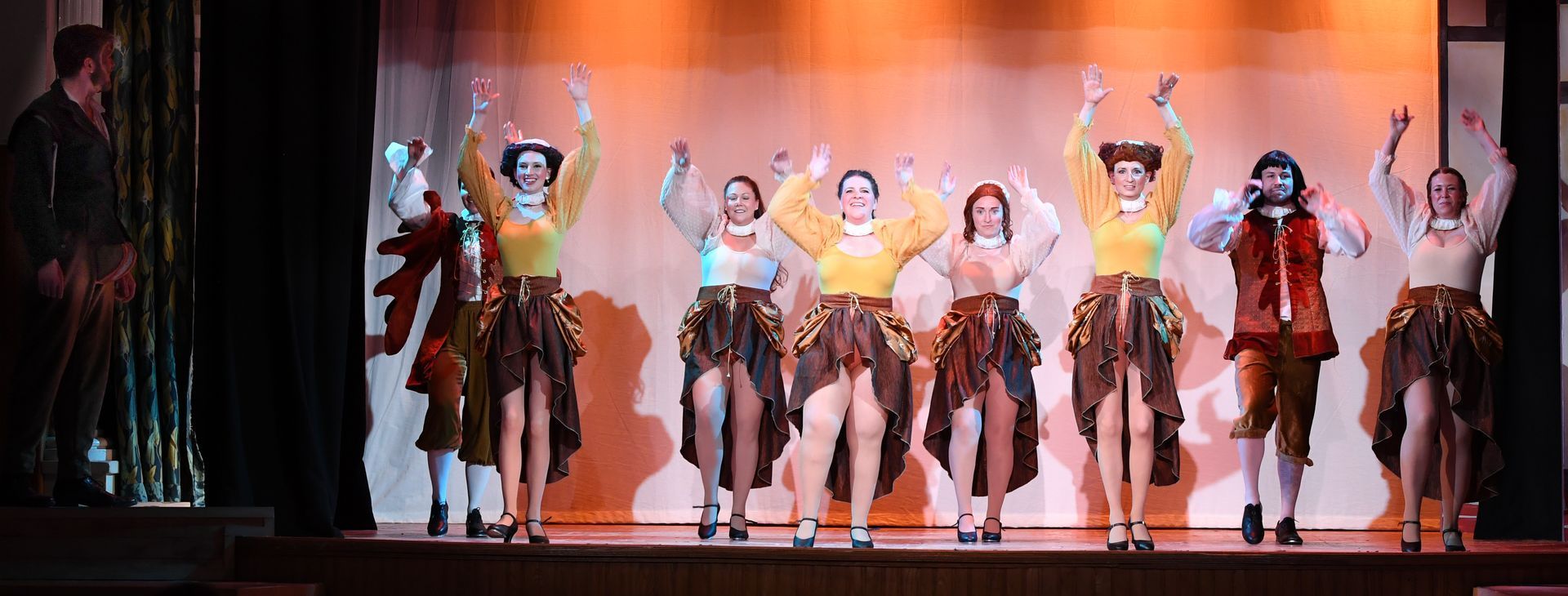 A group of people are dancing on a stage with their arms in the air.