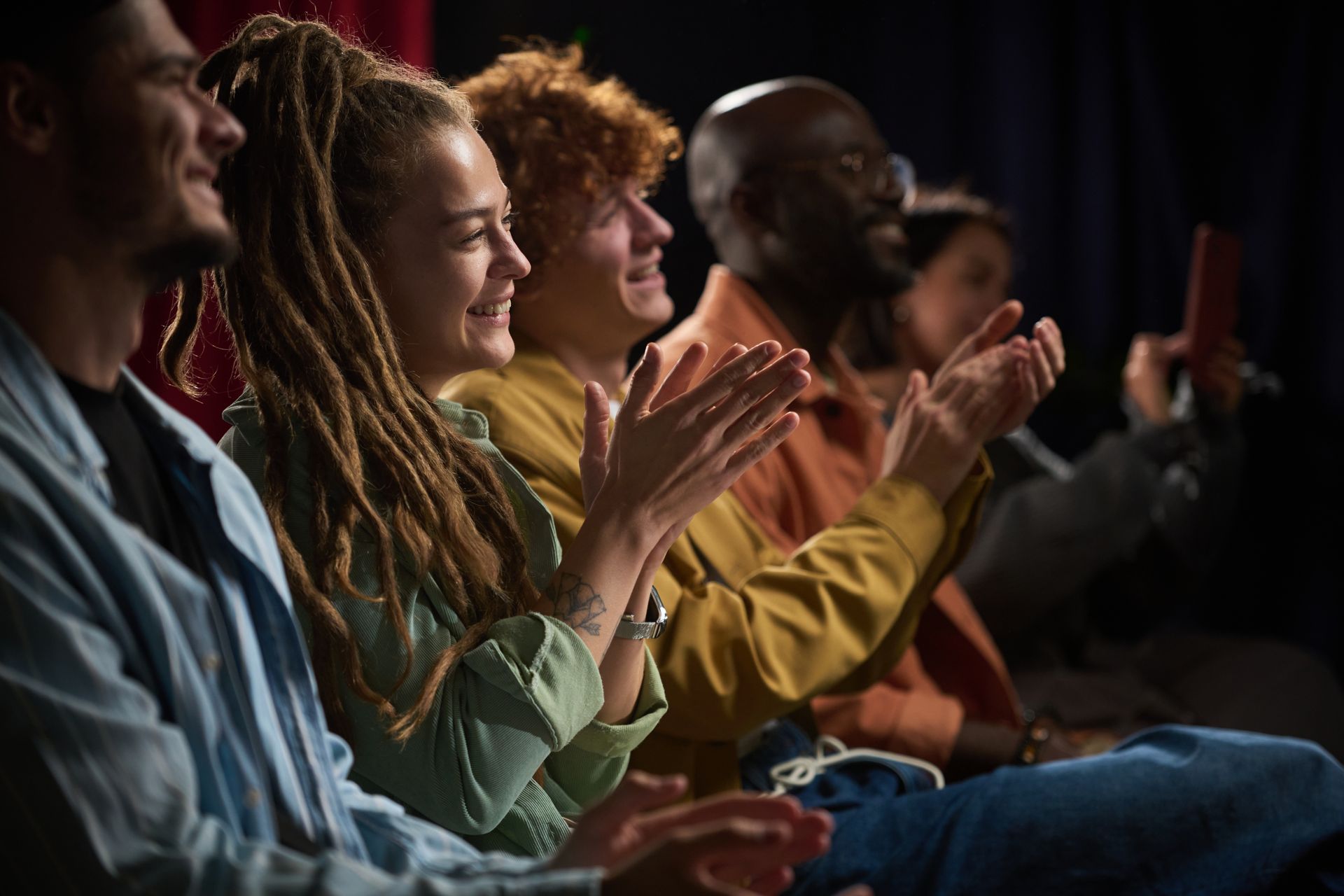 A group of people are sitting in a theater applauding.