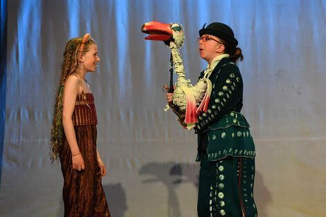 A man and a girl are standing next to each other on a stage holding a toucan.