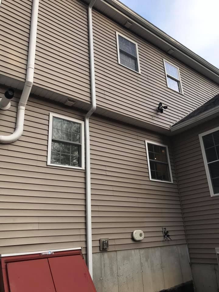 Exterior view of a house with yellow siding, a dark roof, and white gutters.