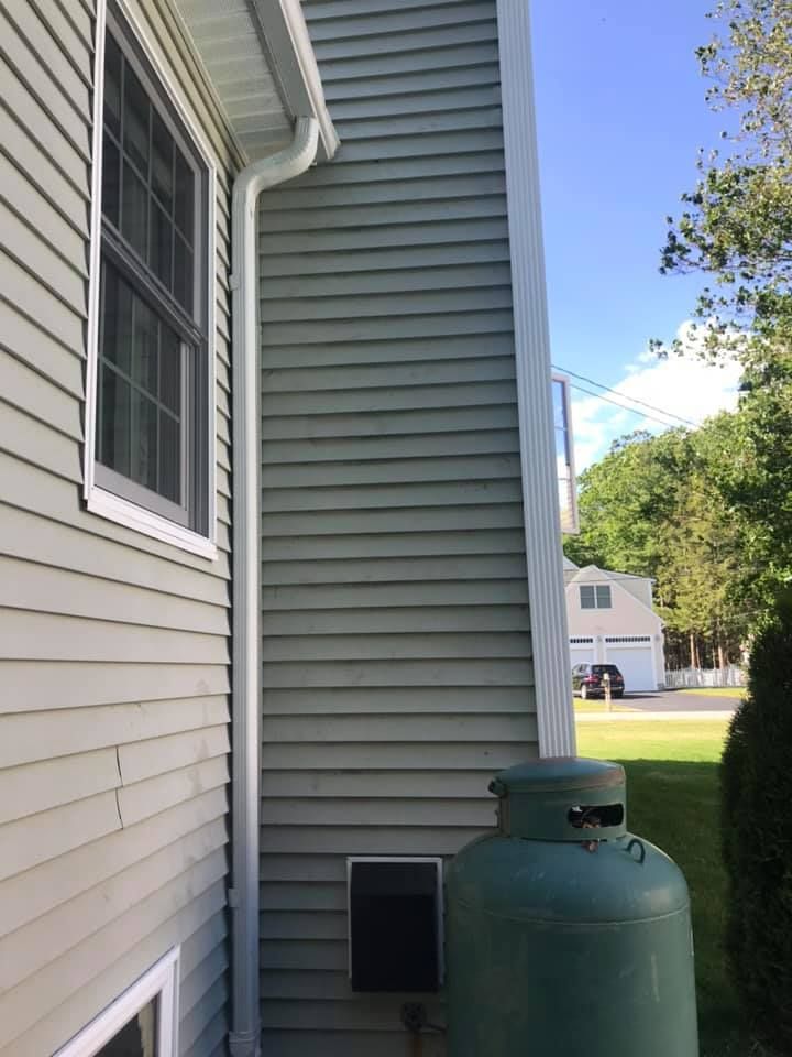 Blue-sided house with white trim, windows, and gutters against a partly cloudy sky.