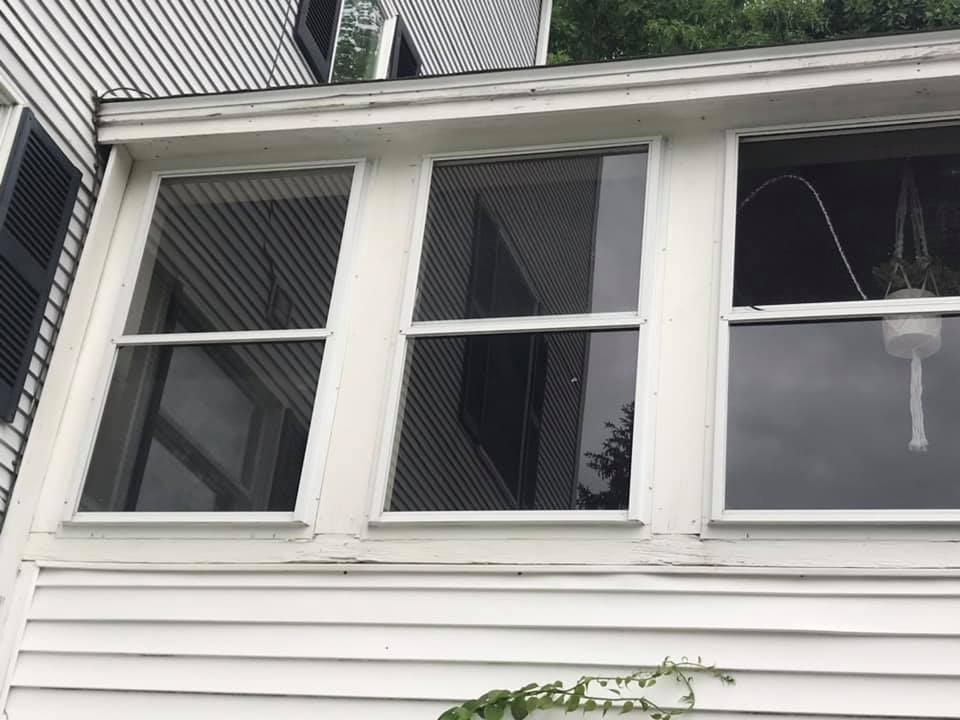 Cottage with screened-in porch, dark roof, and brick chimney under a clear blue sky.