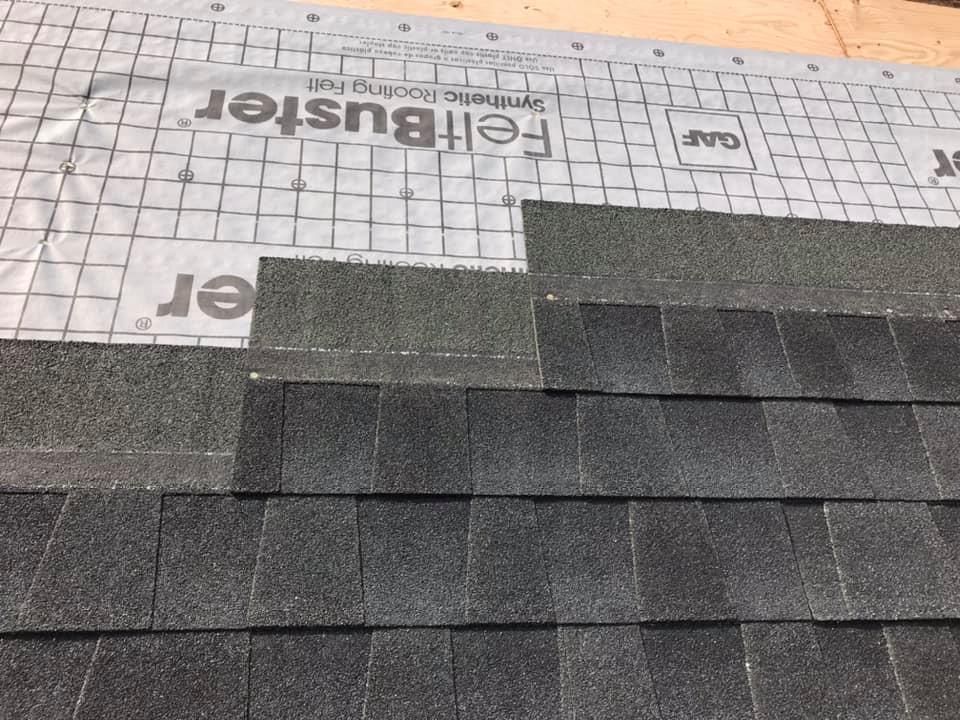 Arched metal-framed structure with a white cover, against a blue sky with some clouds.