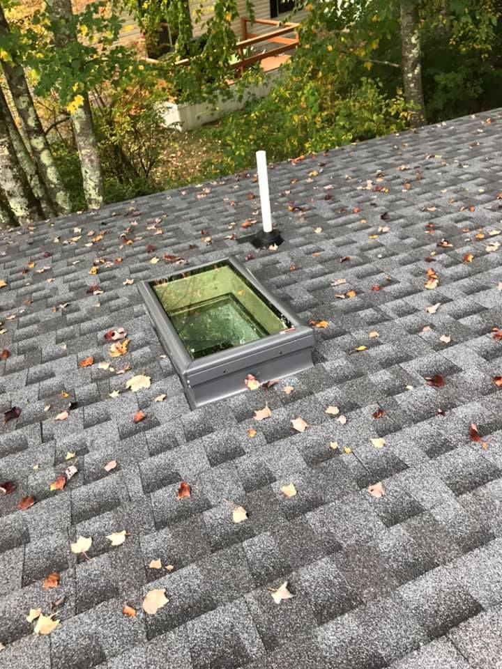 Small house with a screened-in porch, dark roof, and brick chimney against a blue sky.