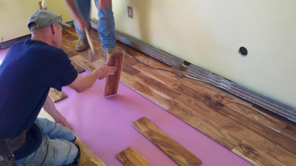 Grey composite deck boards being installed near wooden support posts.