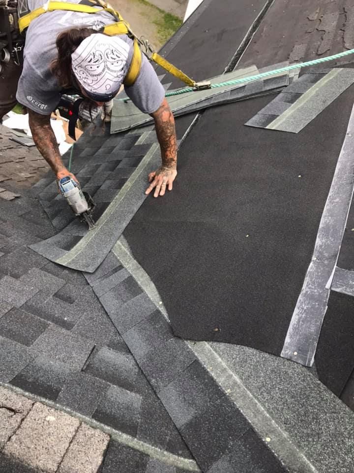 Roofer installing shingles on a roof, using a nail gun.