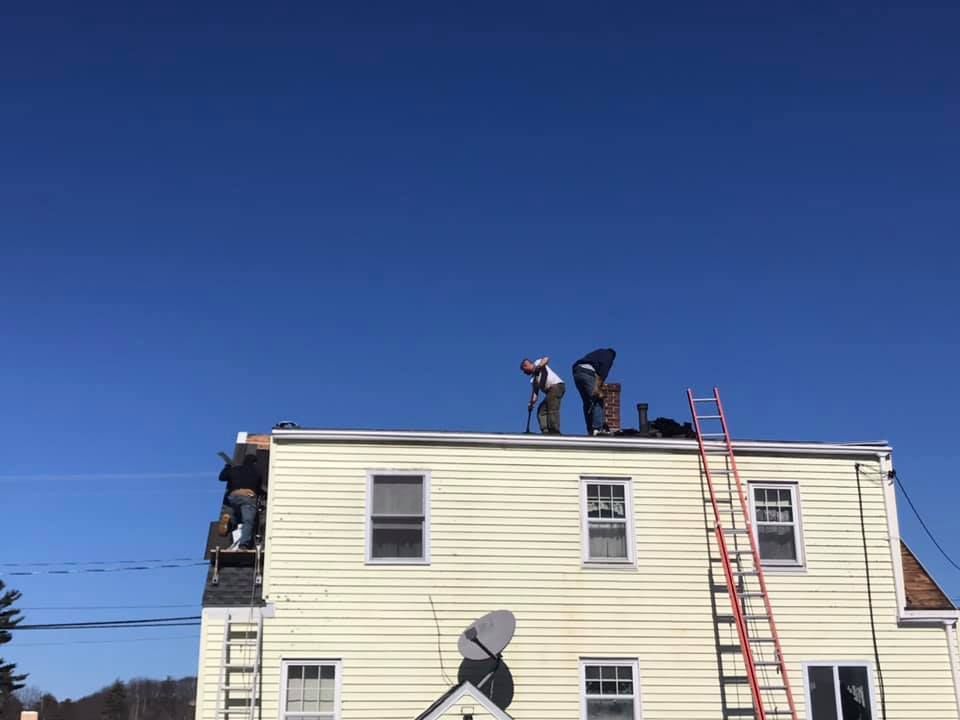Gutter along a dark shingle roof with ladder visible.