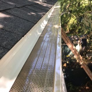 Gutter with a metal mesh cover installed on a roof.
