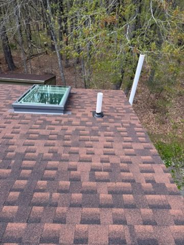 Aerial view of a blue-gray metal roof with multiple vents and angled roof sections.