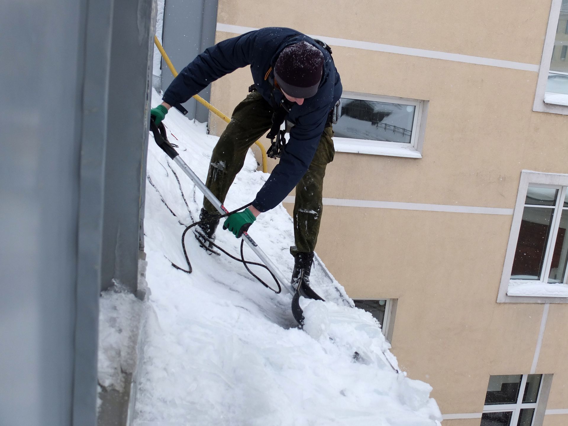 Gutter along a dark shingle roof with ladder visible.