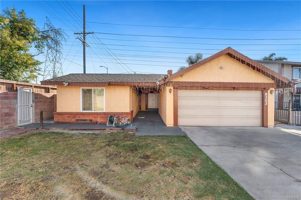 Tan house with attached garage, brown trim, and a small patch of grass.