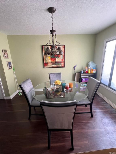 Dining room with glass table, four gray chairs, and art on green wall.
