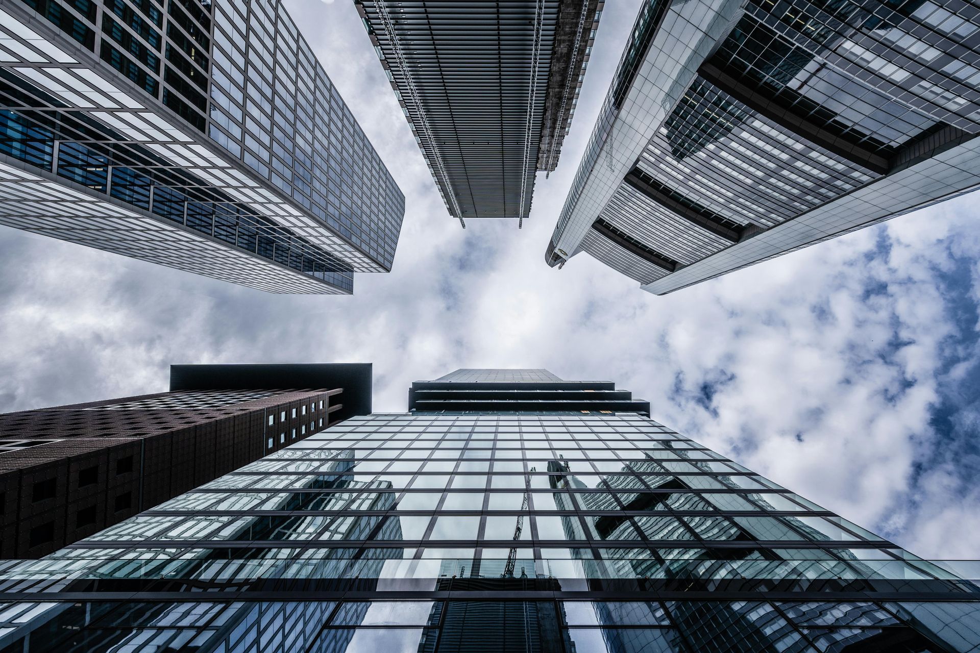 Looking up at modern skyscrapers against a cloudy sky.