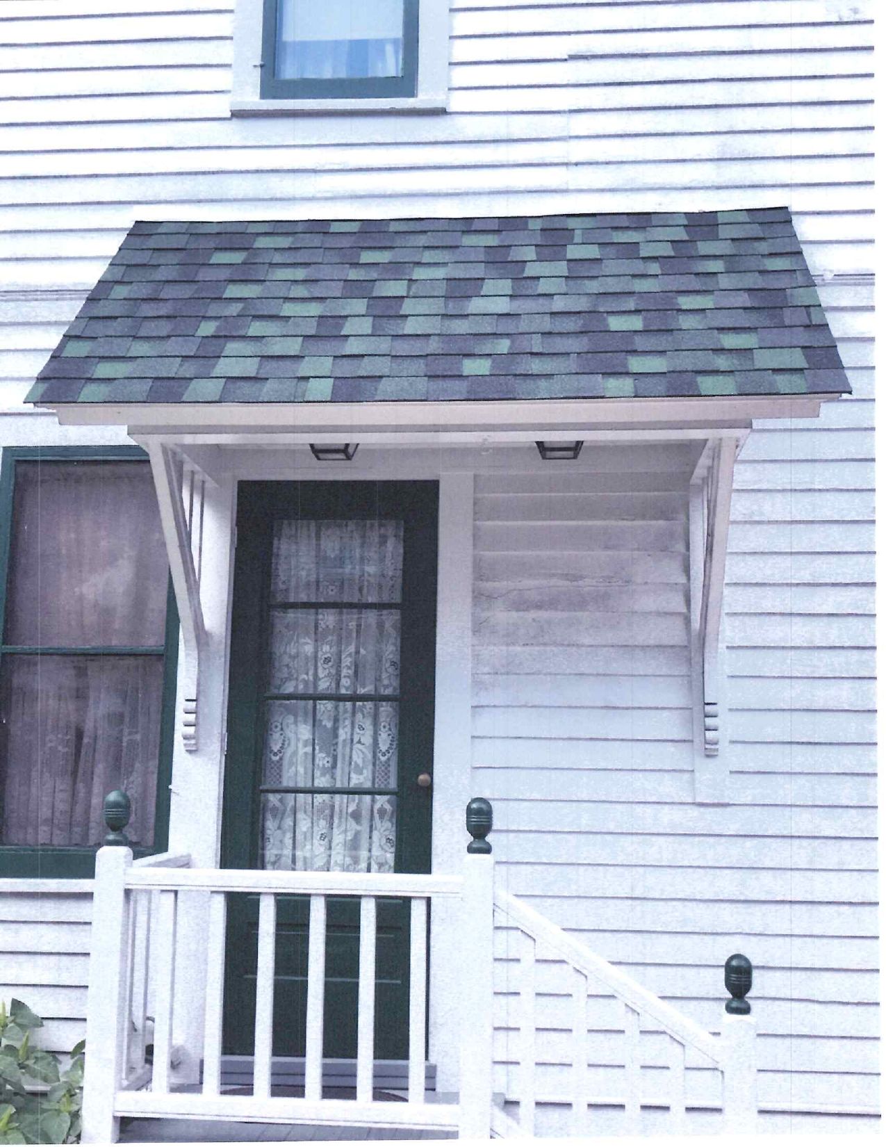 Roofer on a gray shingled roof, laying shingles. Overhead view; light and shadow create texture.