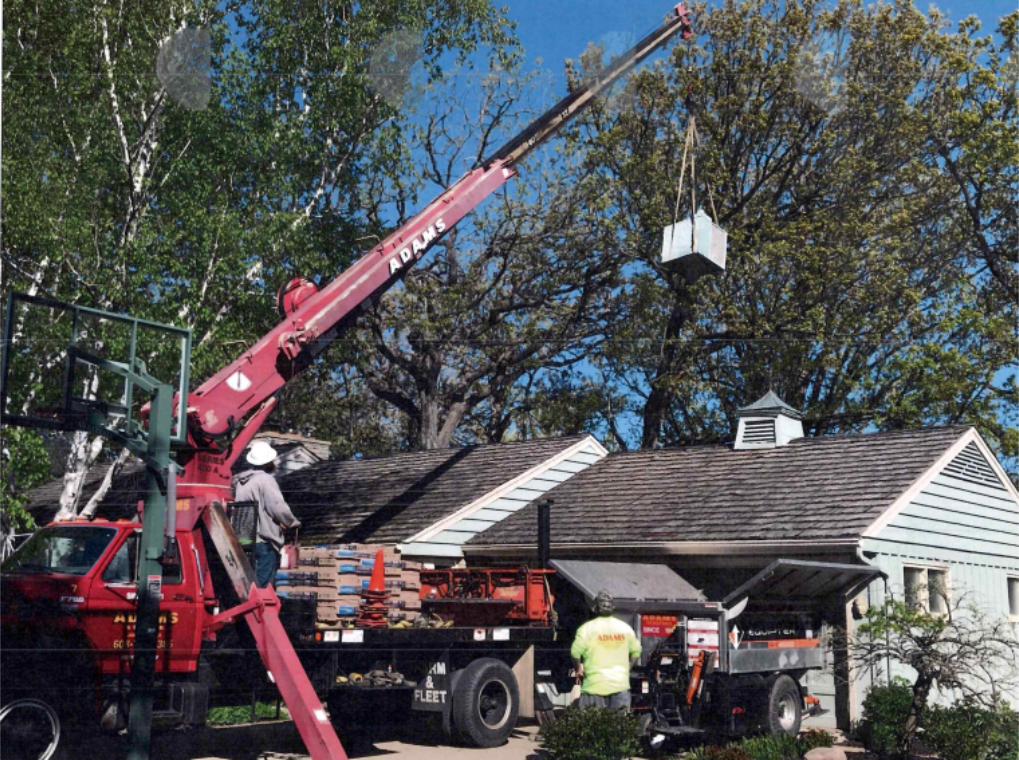 Red sign: Adams Roofing, blue building, snowy ground.