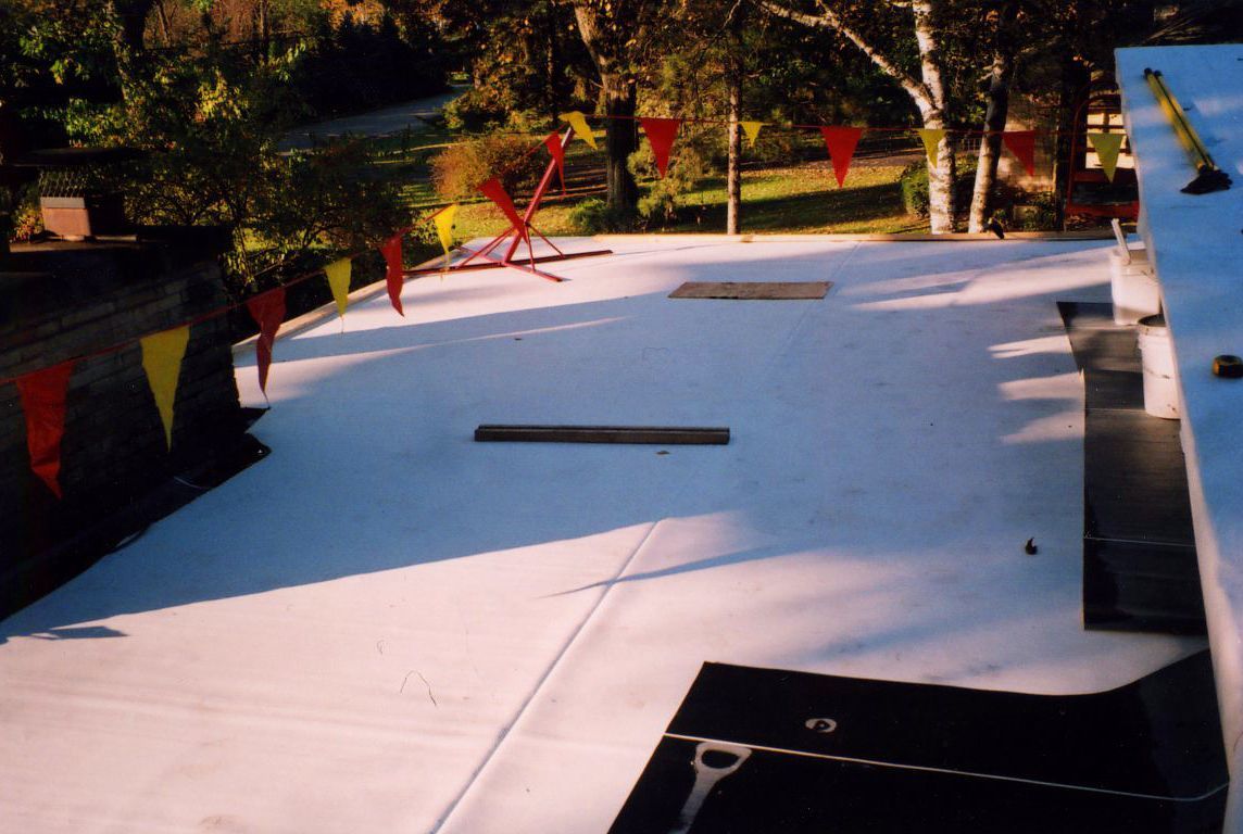White-surfaced outdoor space with red and yellow pennant flags. Trees are visible in the background.