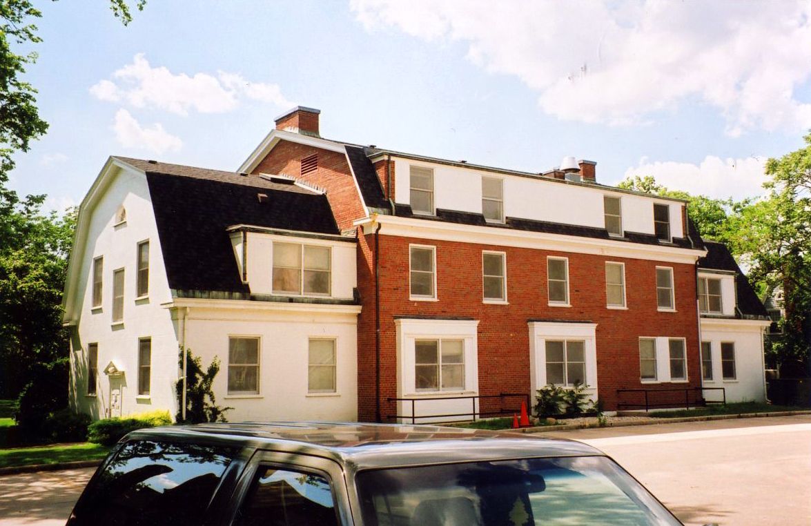 Blue house with white trim, brick accents, and a concrete driveway on a sunny day.