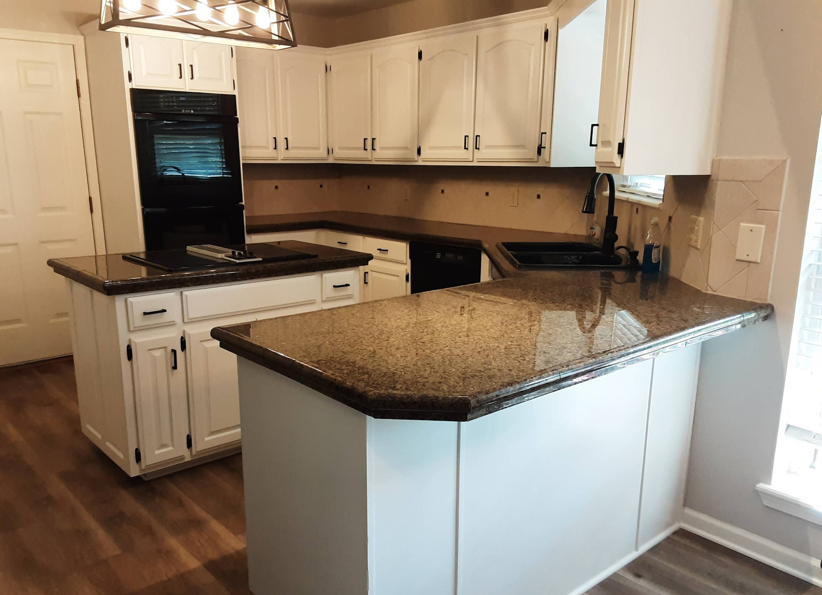 White kitchen with dark countertops and appliances, including a black oven and island.