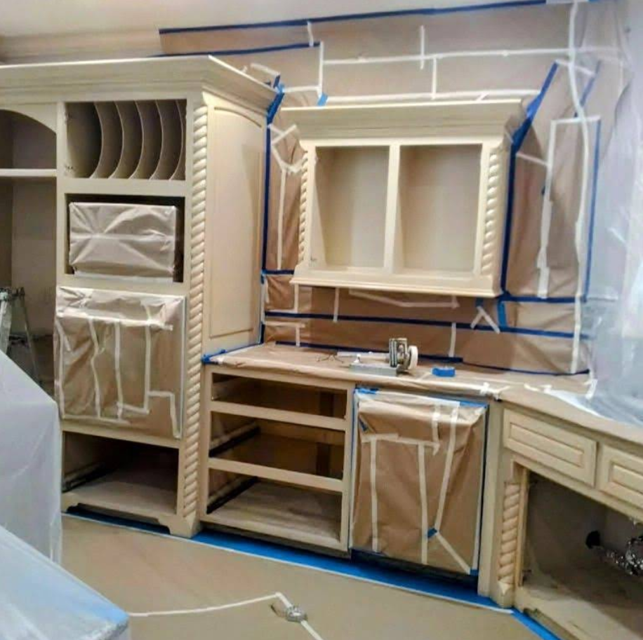Kitchen cabinets, masked with paper and tape, are prepared for painting.