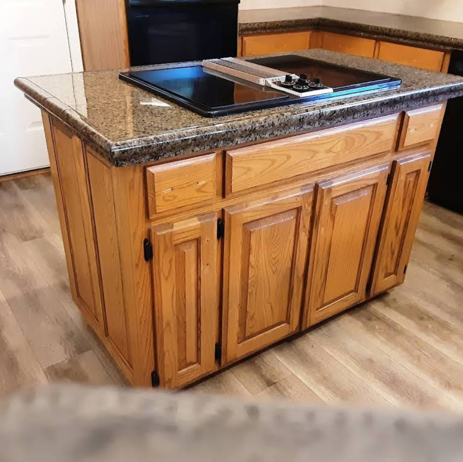 Wooden kitchen island with a cooktop and granite countertop.