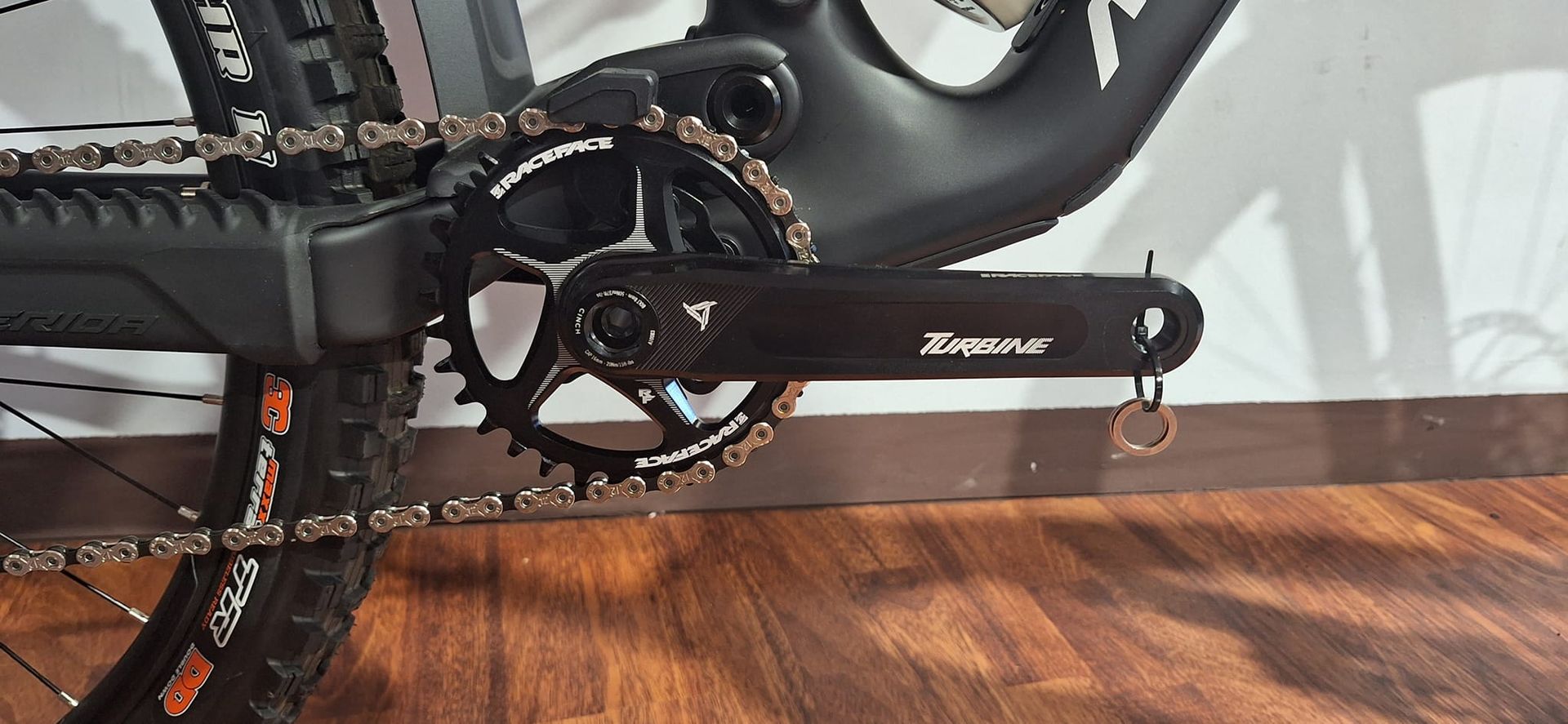 Primo piano di una catena di bicicletta su un pavimento di legno.