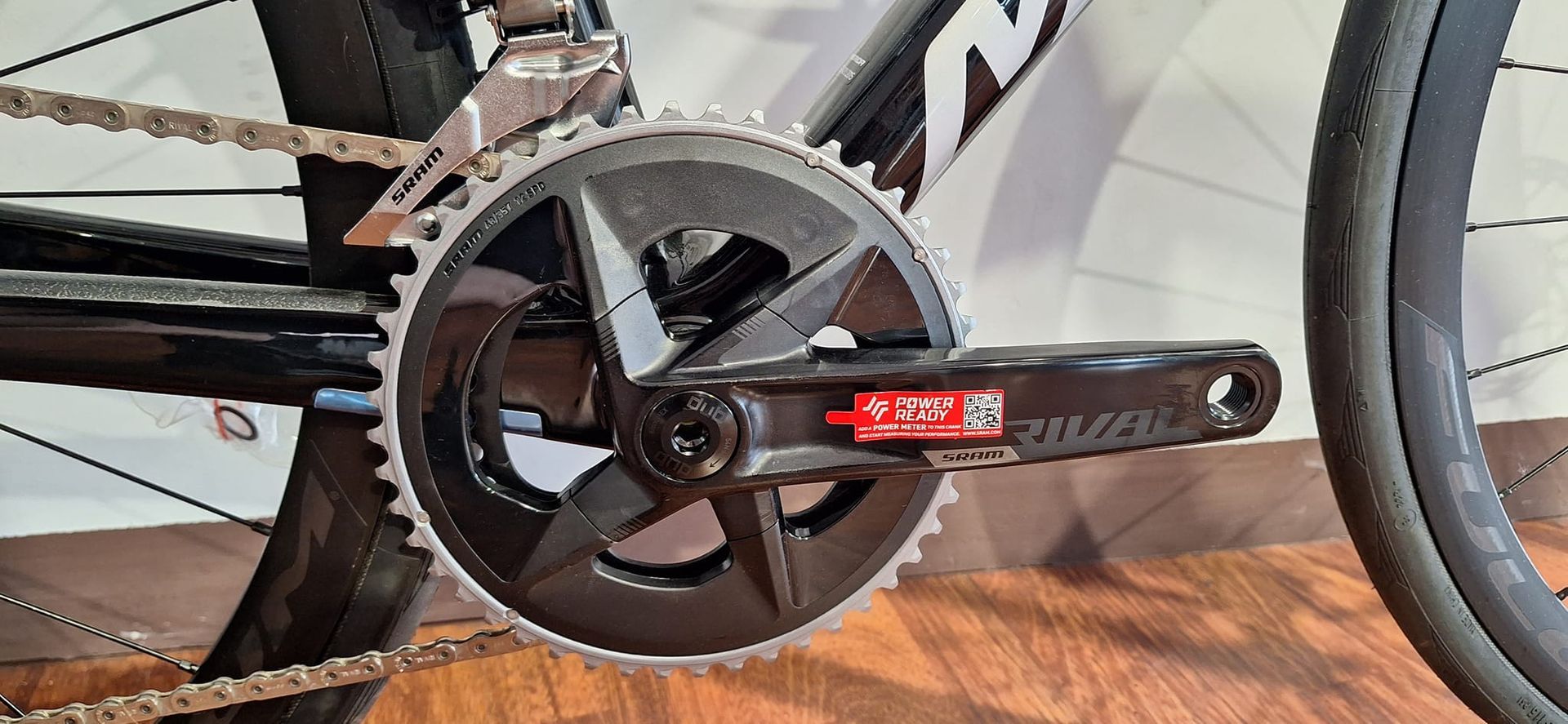 Primo piano di una manovella di bicicletta su un pavimento di legno.
