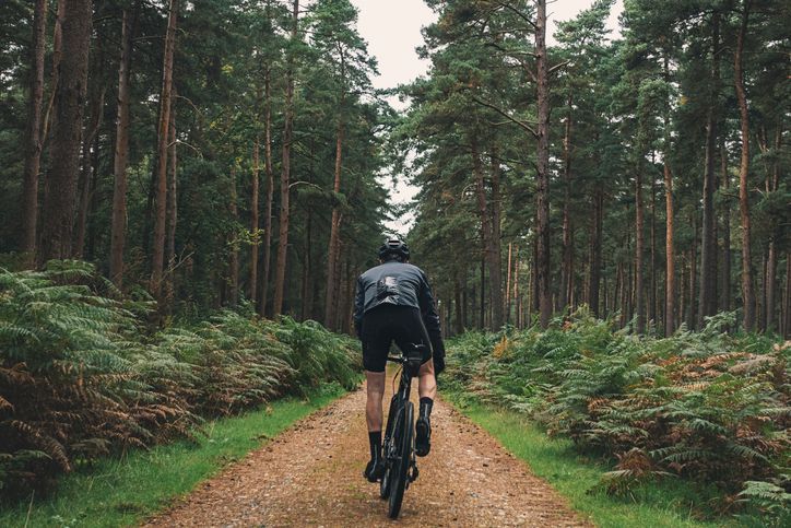 Un uomo sta andando in bicicletta lungo una strada sterrata nel bosco.