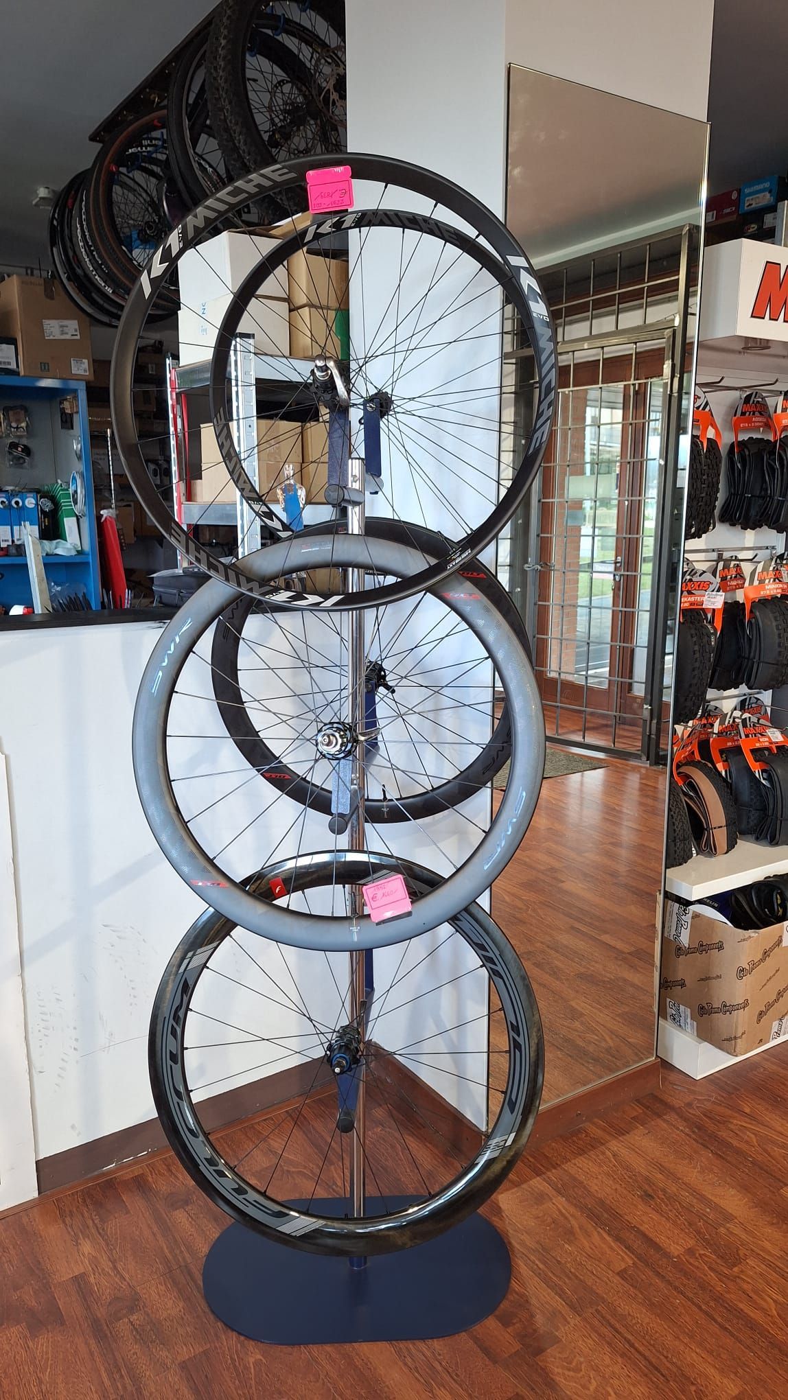 Tre ruote di bicicletta sono impilate l'una sull'altra su un supporto in un negozio.