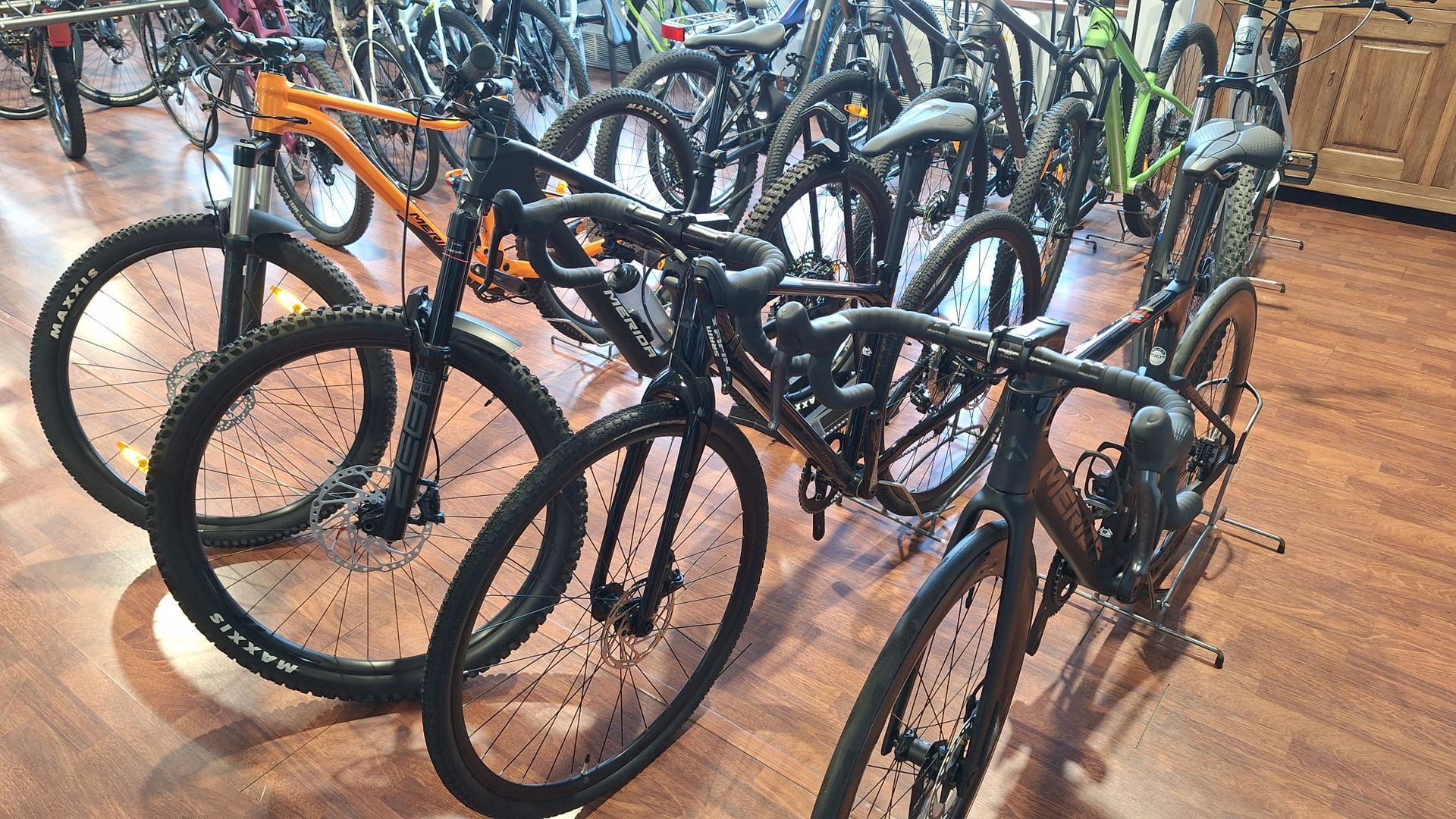 Un mucchio di biciclette è appoggiato su un pavimento di legno in un negozio.
