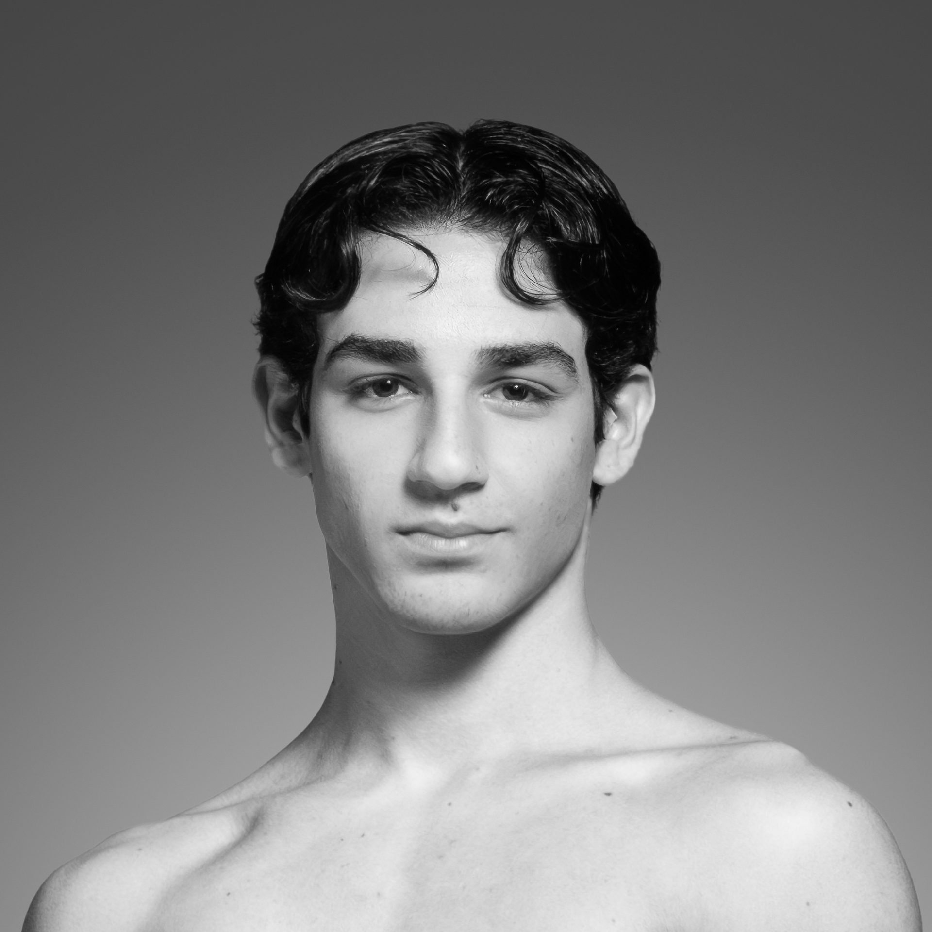 Um jovem sem camisa está olhando para a câmera em uma foto em preto e branco.