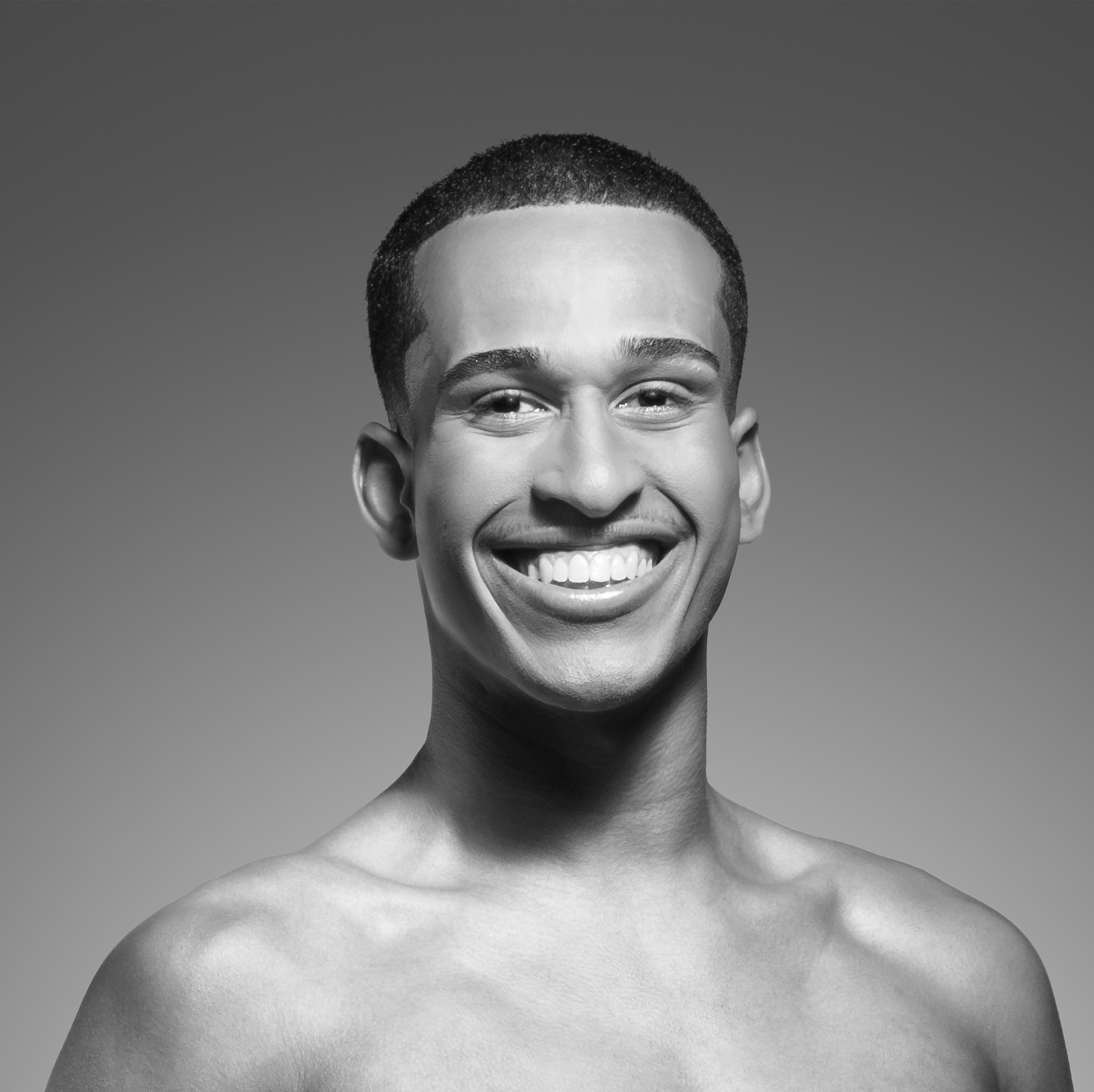 Um homem sem camisa está sorrindo em uma foto em preto e branco.