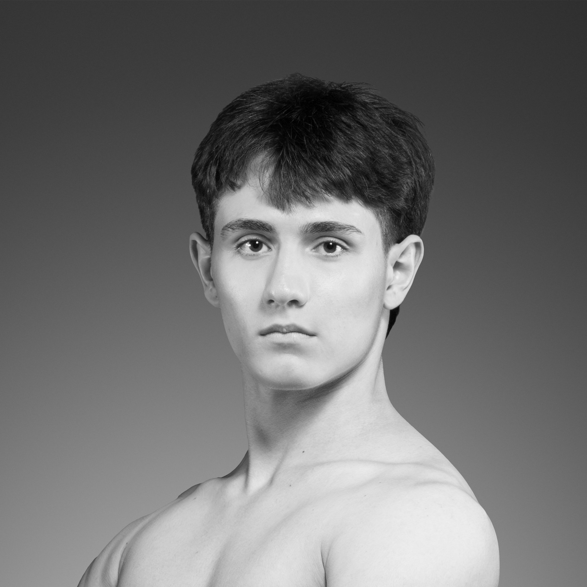 Um jovem sem camisa está olhando para a câmera em uma foto em preto e branco.