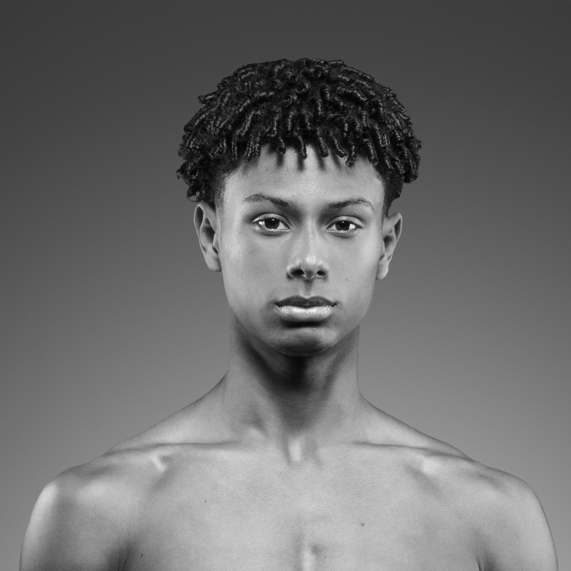 Um jovem sem camisa está olhando para a câmera em uma foto em preto e branco.