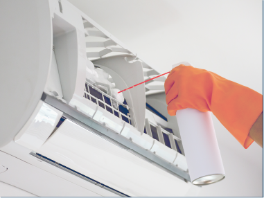 一名戴著橘色手套的人正在向空調通風口噴灑清潔劑。