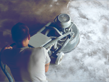 有人正在用大型工業機器打磨混凝土地面；室內環境。