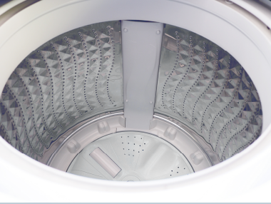 頂部裝載式洗衣機滾筒內部視圖，顯示了帶有圖案的金屬壁和中央攪拌器。