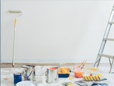 油漆用品：滾筒、油漆罐、油漆刷和梯子，靠著一面白牆。