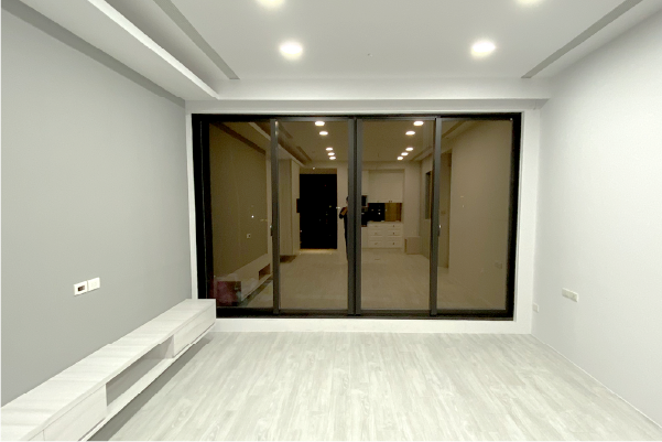 空蕩蕩的房間，牆壁是淺灰色的，地板是白色的，滑動玻璃門通往一個昏暗的室內。