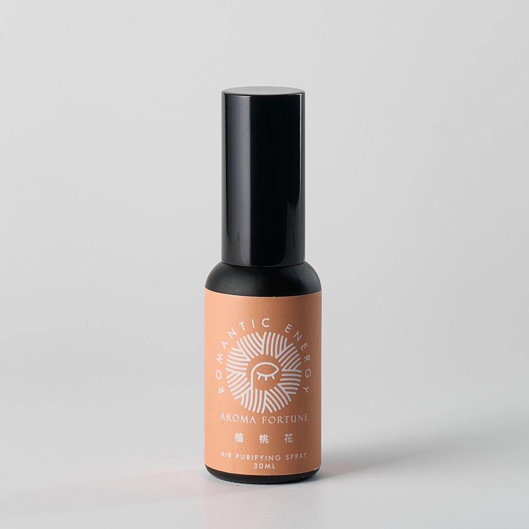 小型化妝品瓶，黑色瓶蓋，桃色標籤。標籤上印有文字和太陽光芒圖案。