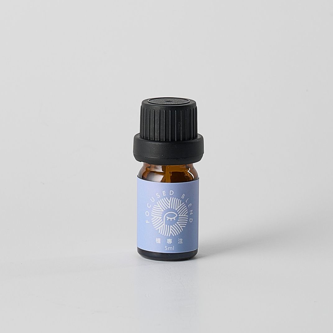 白色背景上的小型琥珀色精油瓶，淺藍色標籤，黑色瓶蓋。