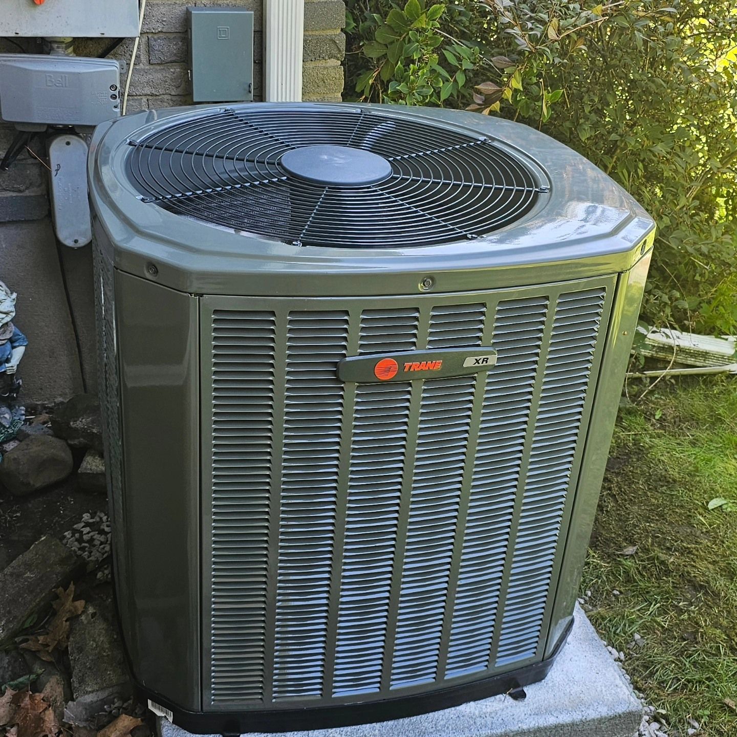 Trane air conditioning unit outside a building; gray with fan on top, and vents in front.